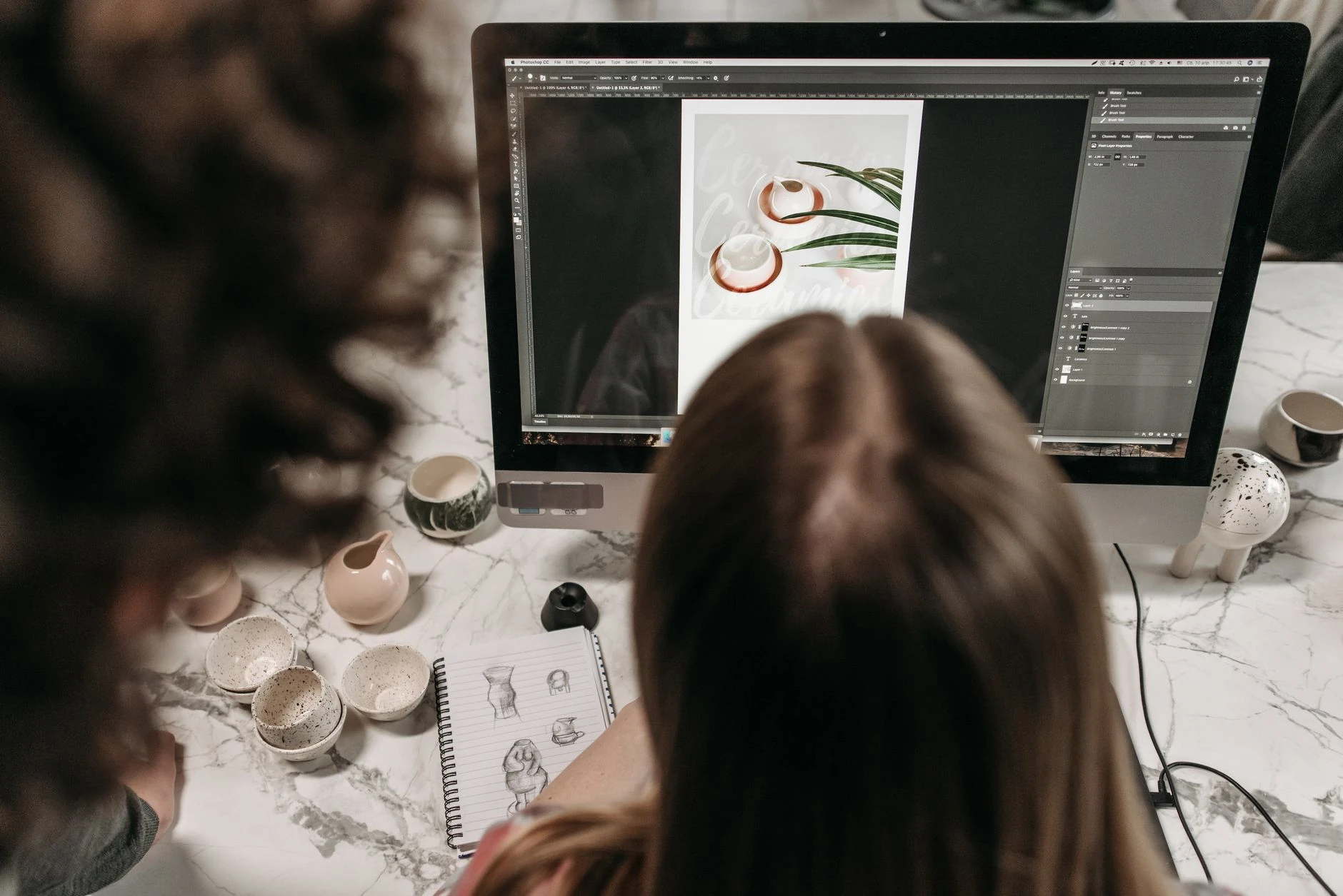 Deux professionnels qui collaborent sur la retouche photo en studio — Formation IA création visuelle et upscaling