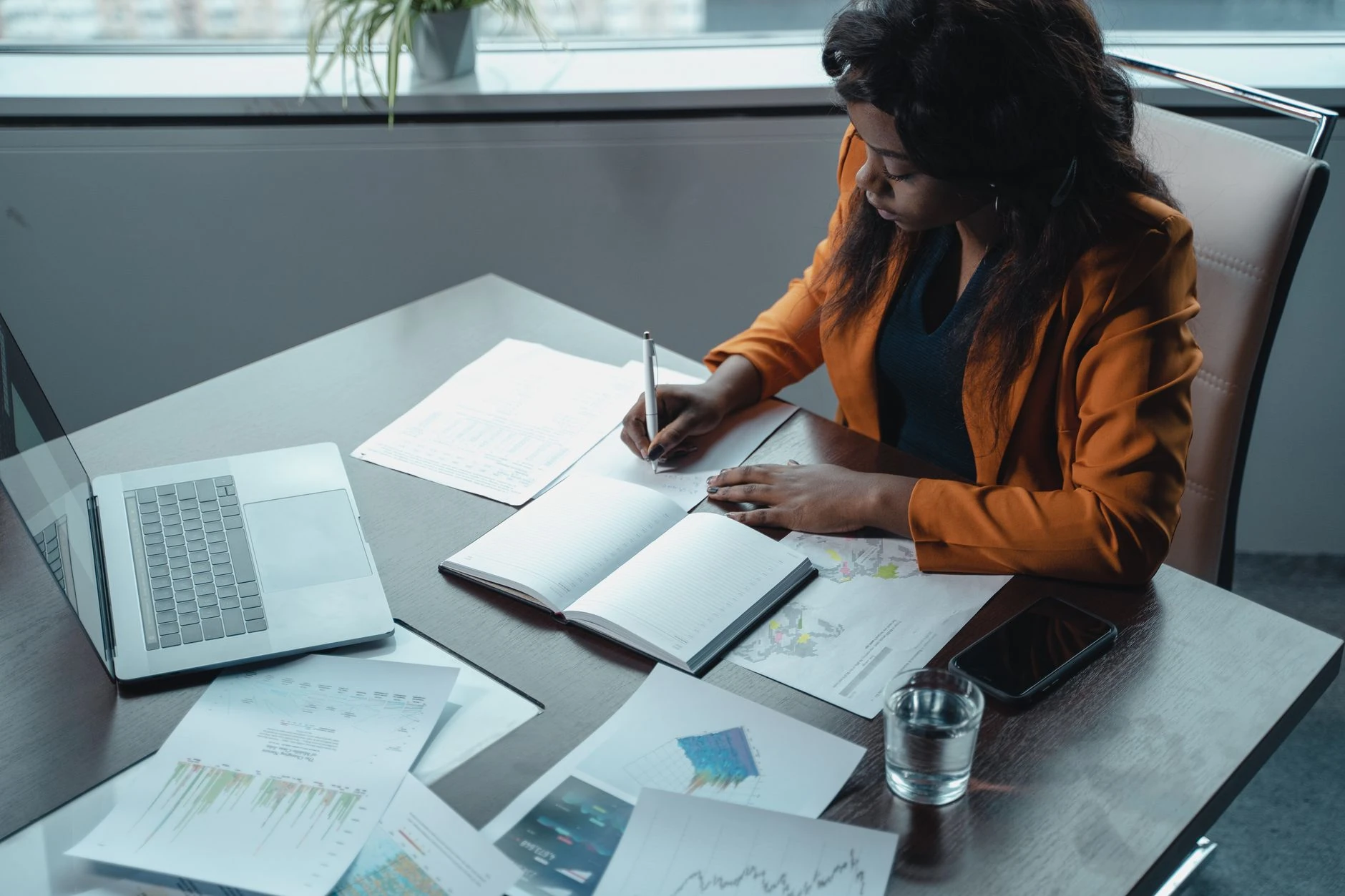 Directrice de communication prenant des notes avec documents et ordinateur portable — Formation IA