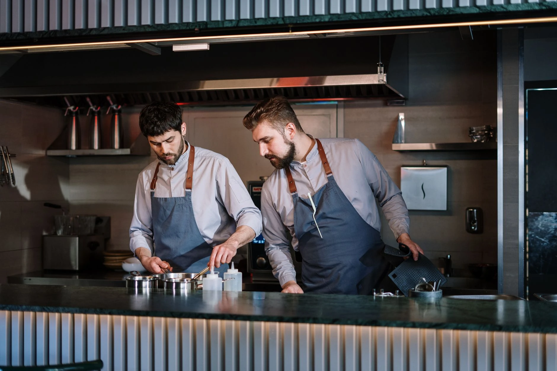 Deux chefs en cuisine ouverte professionnelle — Formation IA pour gérant de restaurant