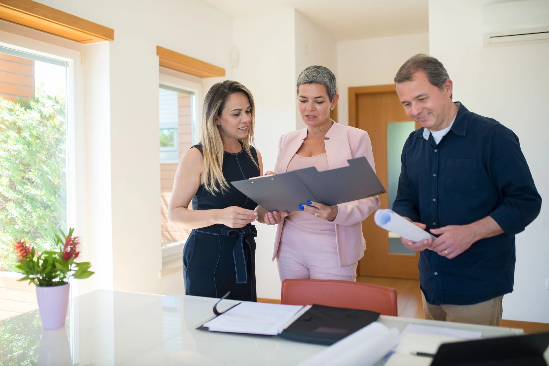 Trois professionnels de l'immobilier qui examinent des documents dans un bureau moderne — Formation IA pour l'immobilier