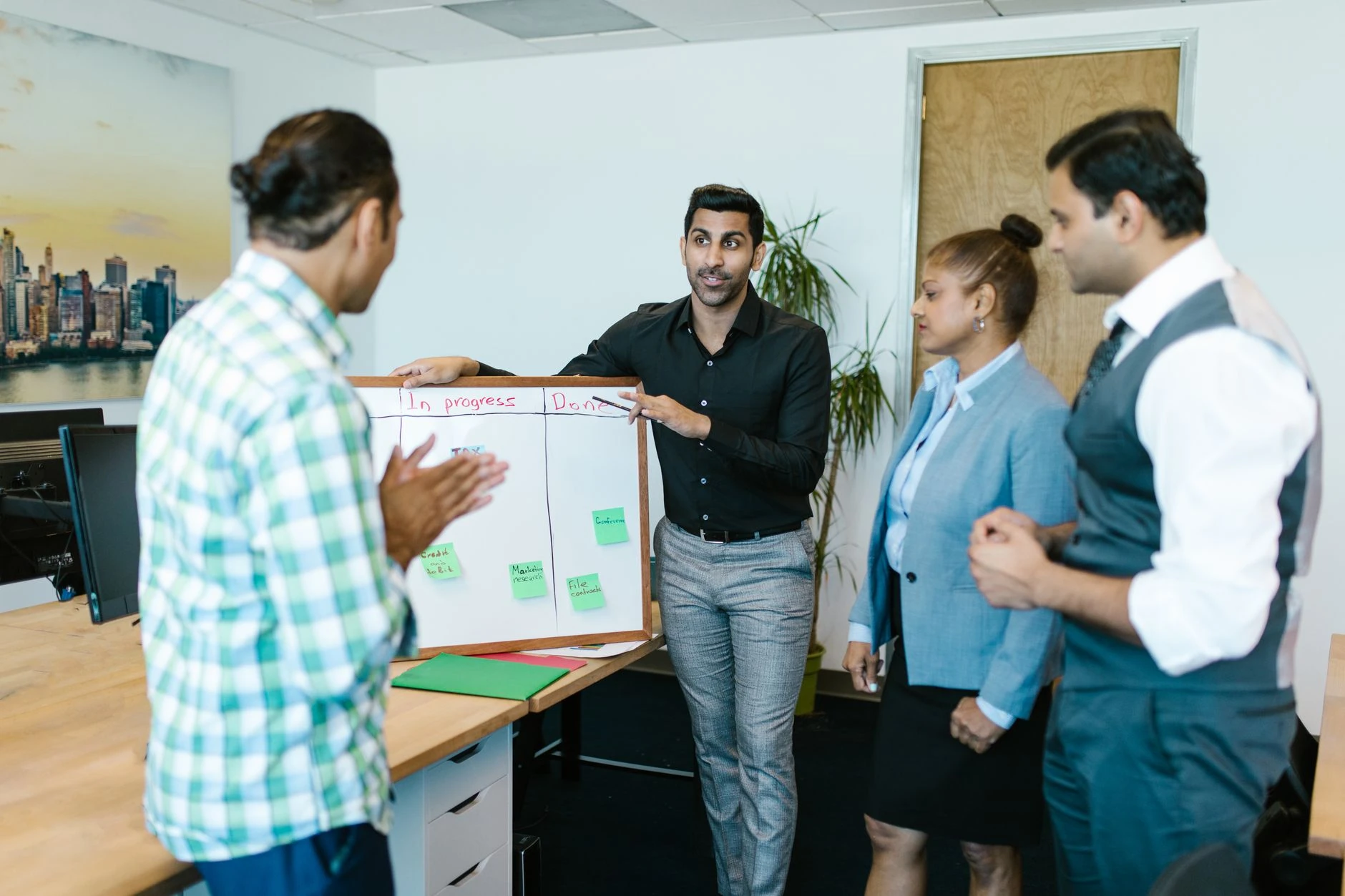 Équipe pluridisciplinaire en réunion agile autour d'un tableau de suivi de projet